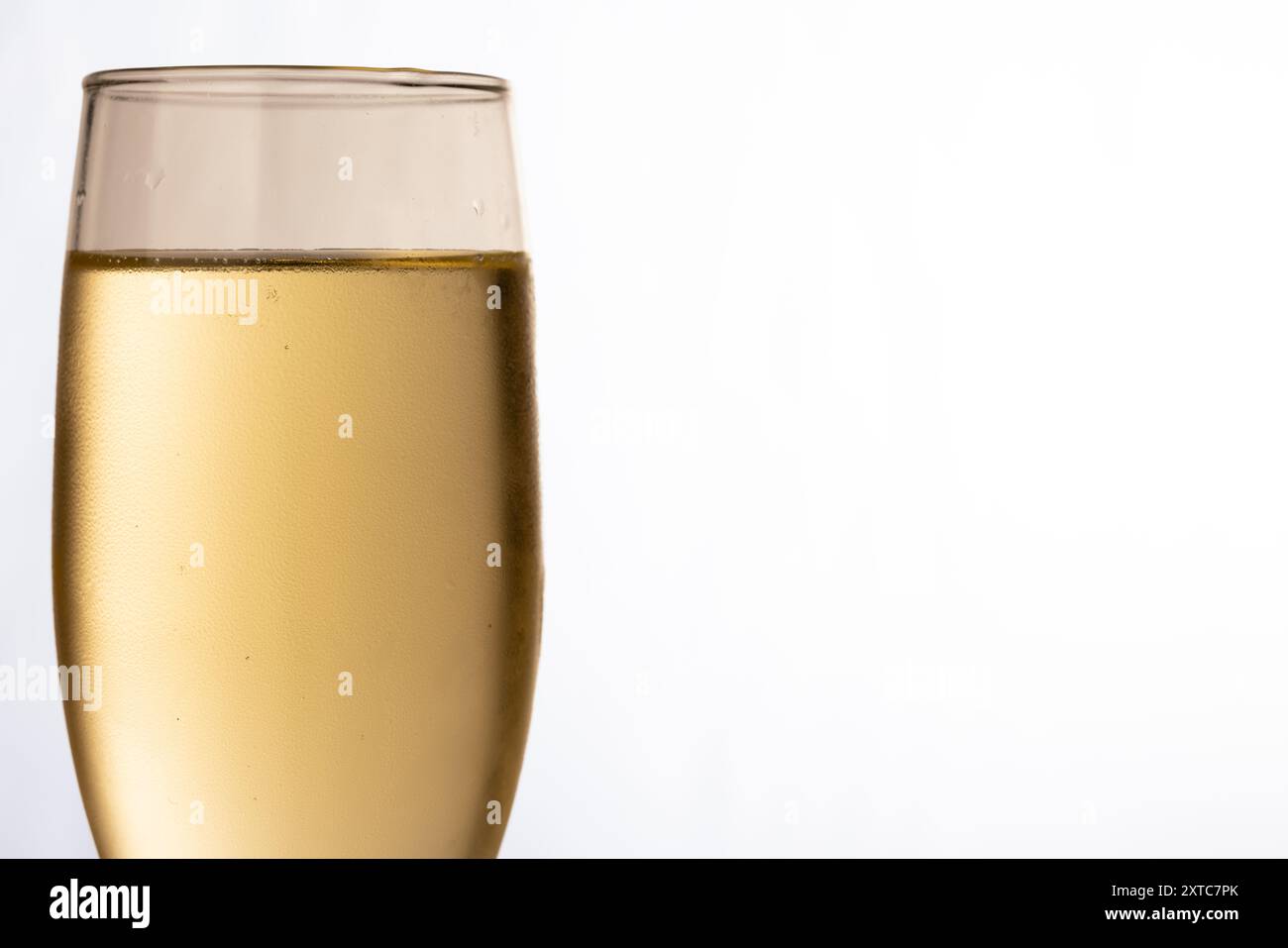 Eine Nahaufnahme eines mit prickelndem Champagner gefüllten Champagnerglases, links auf einem sauberen weißen Hintergrund. Perfekt für festliche Feiern. Stockfoto