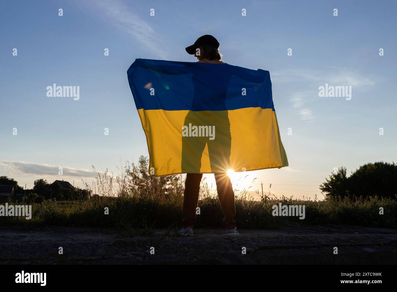 Silhouette einer Frau, die ukrainische Flagge gegen Himmel und untergehende Sonne hält. Unabhängigkeitstag der Ukraine. Freiheit, Stolz, Nationalsymbol. Support Ukr Stockfoto