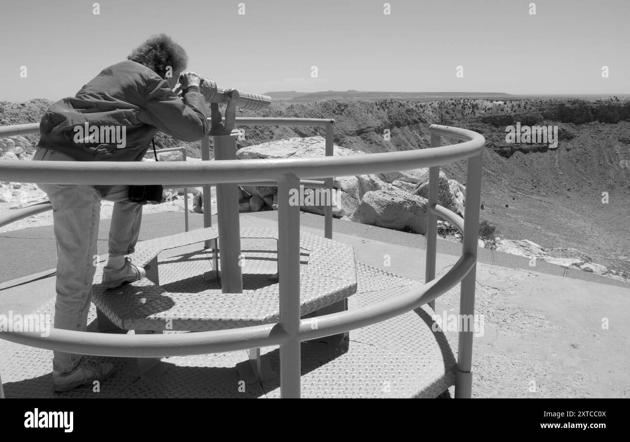 Eine kaukasische Frau im Alter von 50-60 Jahren sieht den beeindruckenden Meteor-Krater entlang der Route 66 in der Nähe von Winslow, Arizona, USA. Stockfoto