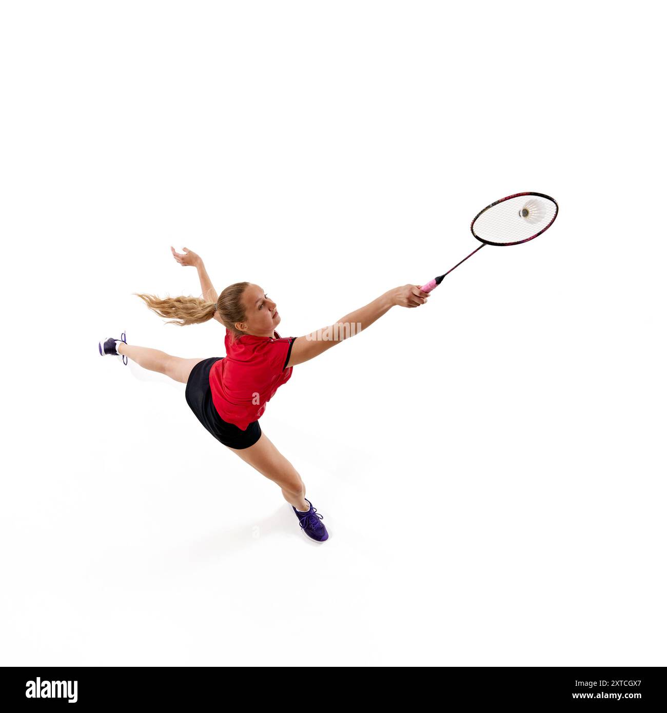 Luftaufnahme eines weiblichen Badmintonspielers, der in Bewegung springt, um Shuttlecock vor weißem Studiohintergrund zu treffen. Stockfoto