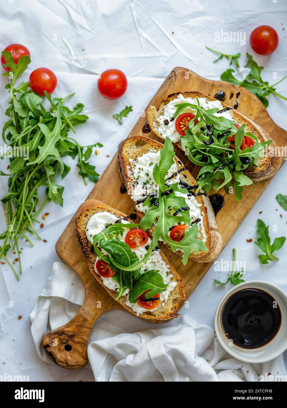 Brotscheibe mit Frischkäse und Salat auf einem Brett, weißer Hintergrund, Rezepte, Lebensmittelfotografie, Zutaten, Ernährung Stockfoto