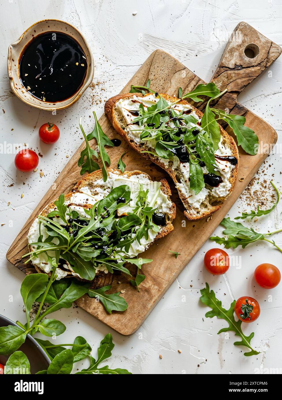 Brotscheibe mit Frischkäse und Salat auf einem Brett, weißer Hintergrund, Rezepte, Lebensmittelfotografie, Zutaten, Ernährung Stockfoto