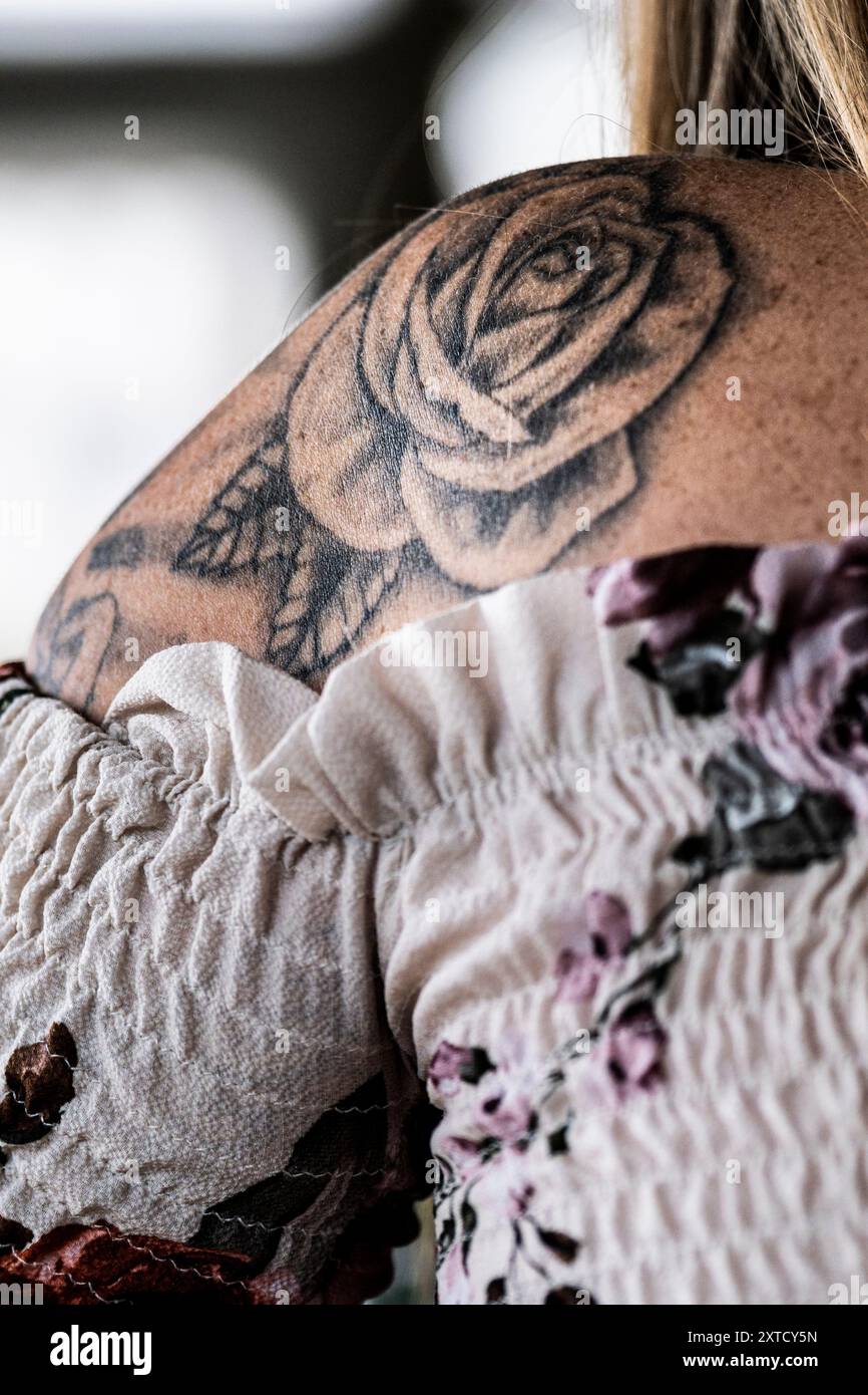 Eine Tätowierung einer Rose auf der Schulter einer Frau in Cornwall im Vereinigten Königreich. Stockfoto