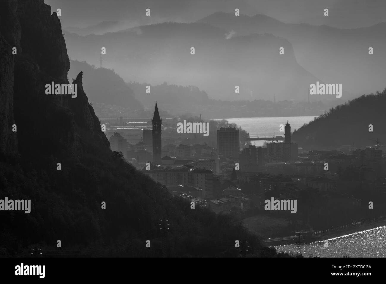 Blick auf die Stadt im Nebel zwischen den Bergen und dem See in Lecco in Italien Stockfoto