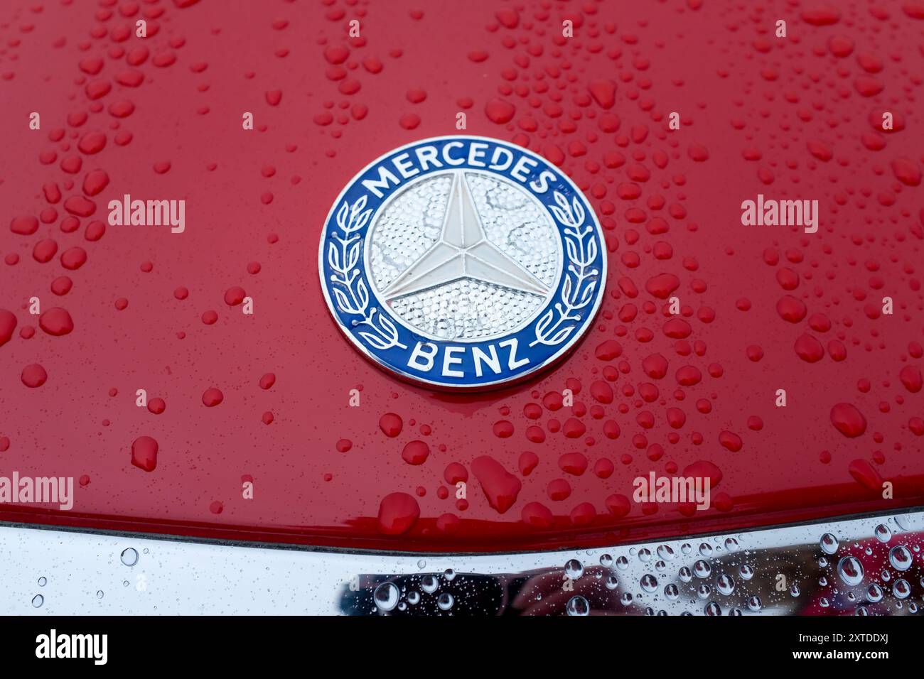 Vintage-Mercedes-Benz-Emblem mit Regentropfen auf rotem Lack. UK. Stockfoto