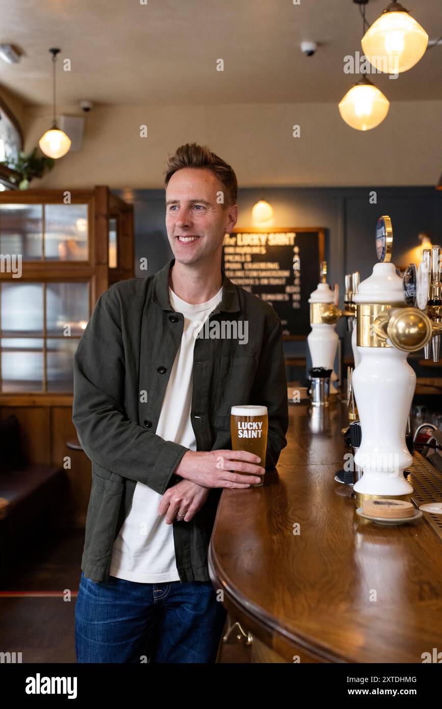 Luke Boase, Gründer und CEO der alkoholfreien Biermarke Lucky Saint, fotografierte mit seinem alkoholfreien Bier in einem Londoner Pub in England, Großbritannien Stockfoto