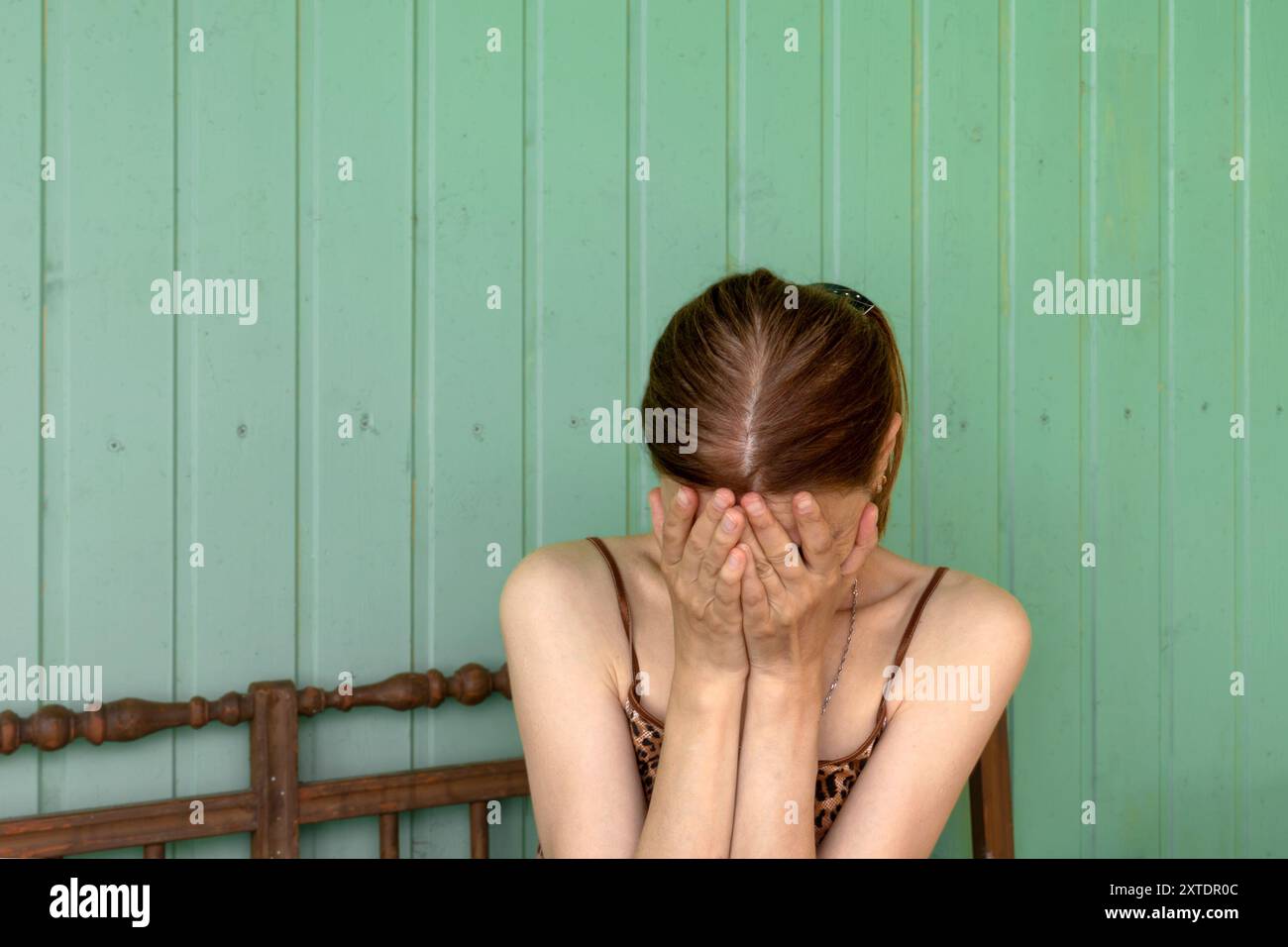 Eine nicht erkennbare junge Frau bedeckte ihr Gesicht mit ihren Handflächen und drückte Verzweiflung und Trauer aus. Kopierbereich. Stockfoto