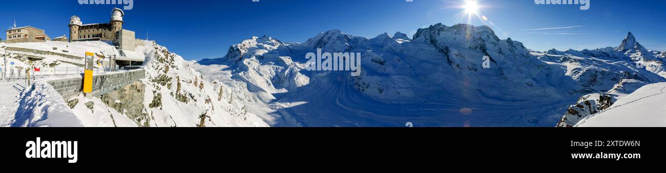 Schnee bedeckt die Alpen am Bahnhof Gornergrat und bietet atemberaubende Ausblicke auf die Berge, während das Matterhorn von heller Wintersonne beleuchtet wird. Stockfoto