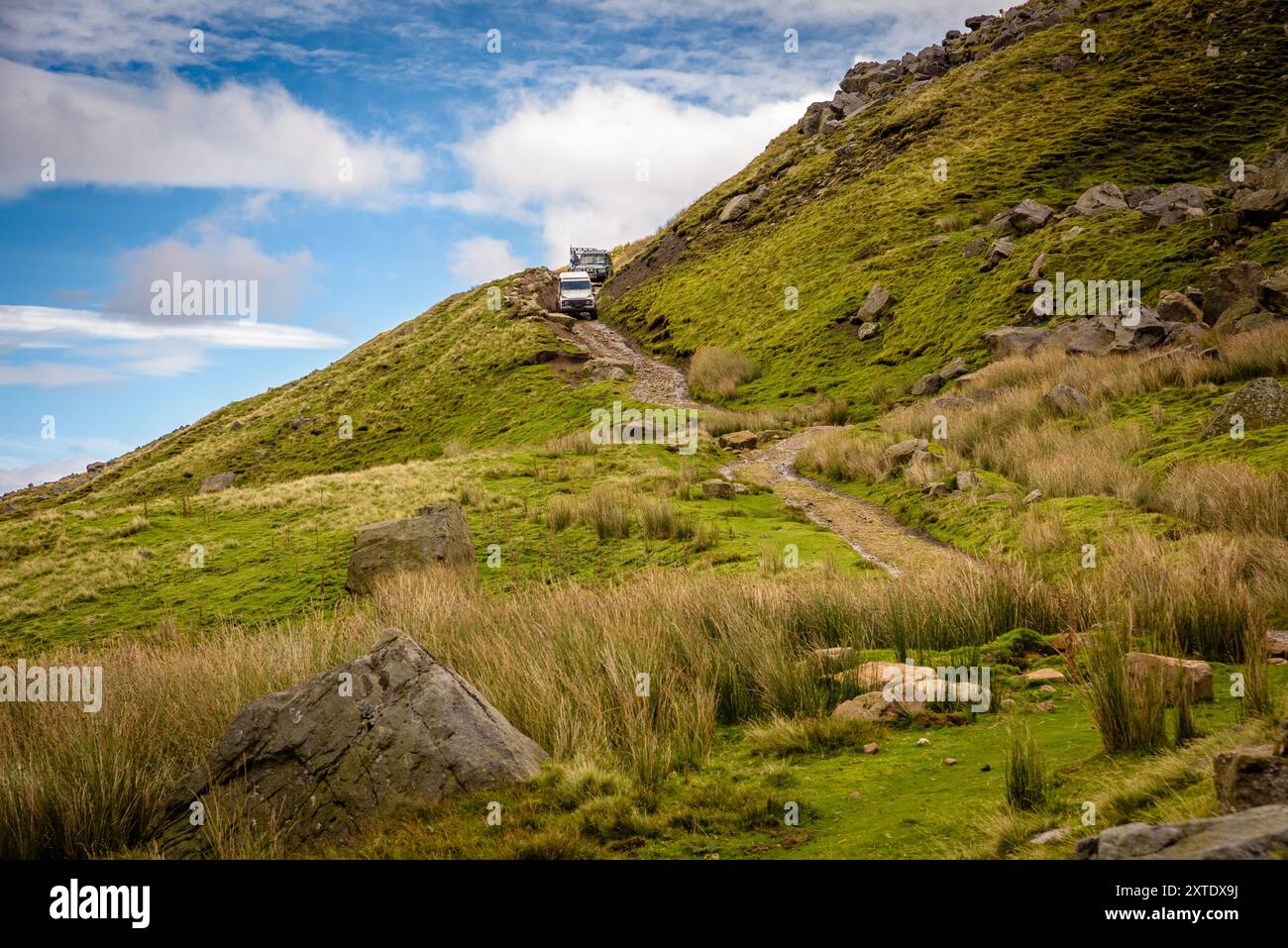 Eine kleine Gruppe von Geländewagen fährt einen steilen, grasbewachsenen Hügel in den Yorkshire Dales hinab und erkundet die natürliche Schönheit der Landschaft. Stockfoto