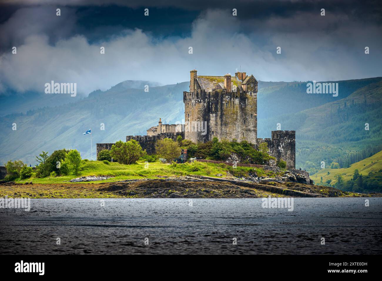 Eilean Donan Castle steht majestätisch auf einer Insel, umgeben von Wasser und Bergen, mit Wolken über den schottischen Highlands. Stockfoto