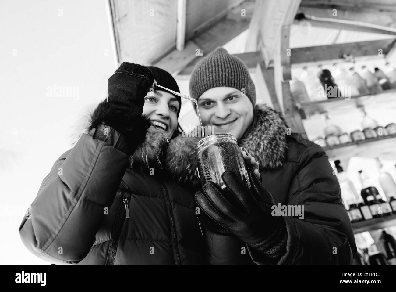Fröhliche Mädchen und Kerl in warmen Winterkleidung an der Markt Probieren Sie Honig und Getränke Stockfoto