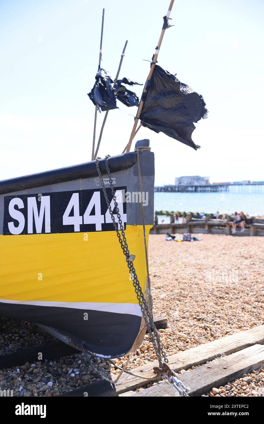 Fischerboot am Worthing Beach, mit dem Pier dahinter, in West Sussex, Großbritannien Stockfoto