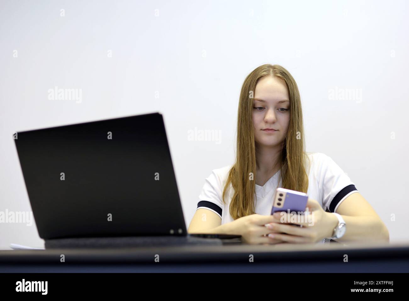 Mädchen mit Smartphone und Laptop am Tisch. Konzept der Online-Kommunikation, Büroarbeit und Bezahlung Stockfoto