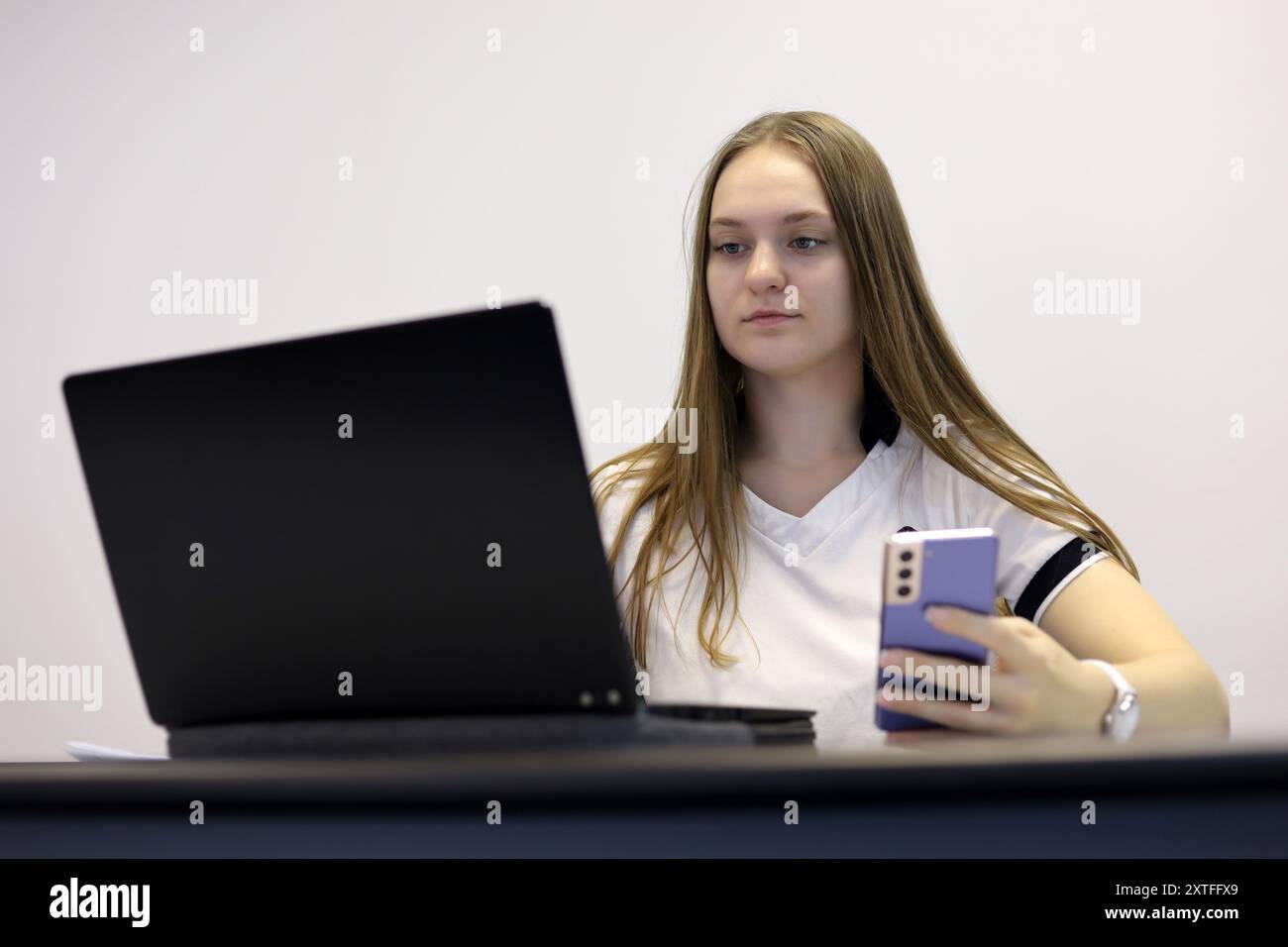 Mädchen mit Smartphone und Laptop am Tisch. Konzept der Online-Kommunikation, Büroarbeit und Bezahlung Stockfoto