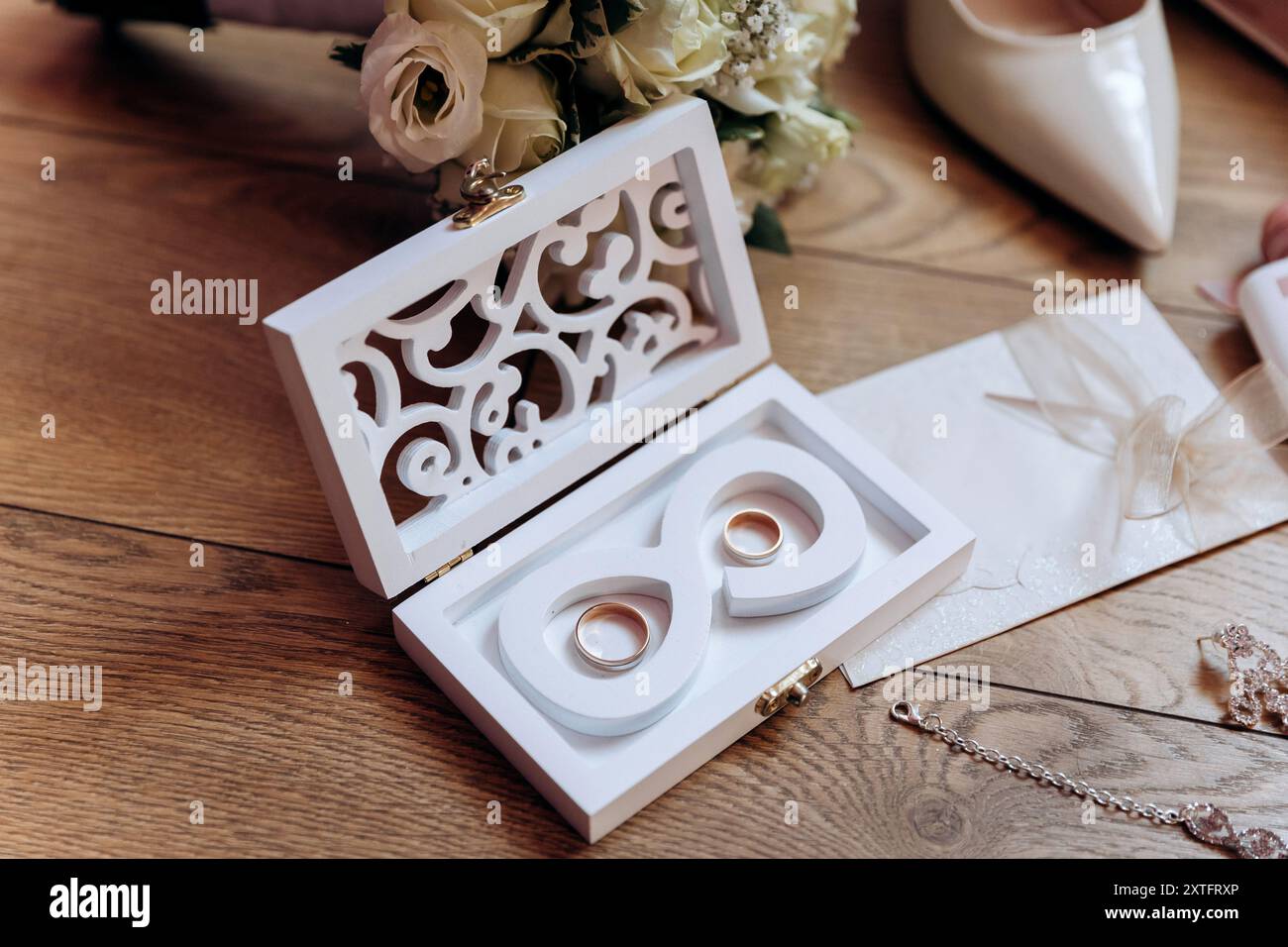 Brautjungfernkostüme: Absatzschuhe, Blumenstrauß, Ringe, Parfüm und Einladung auf dem Tisch Stockfoto