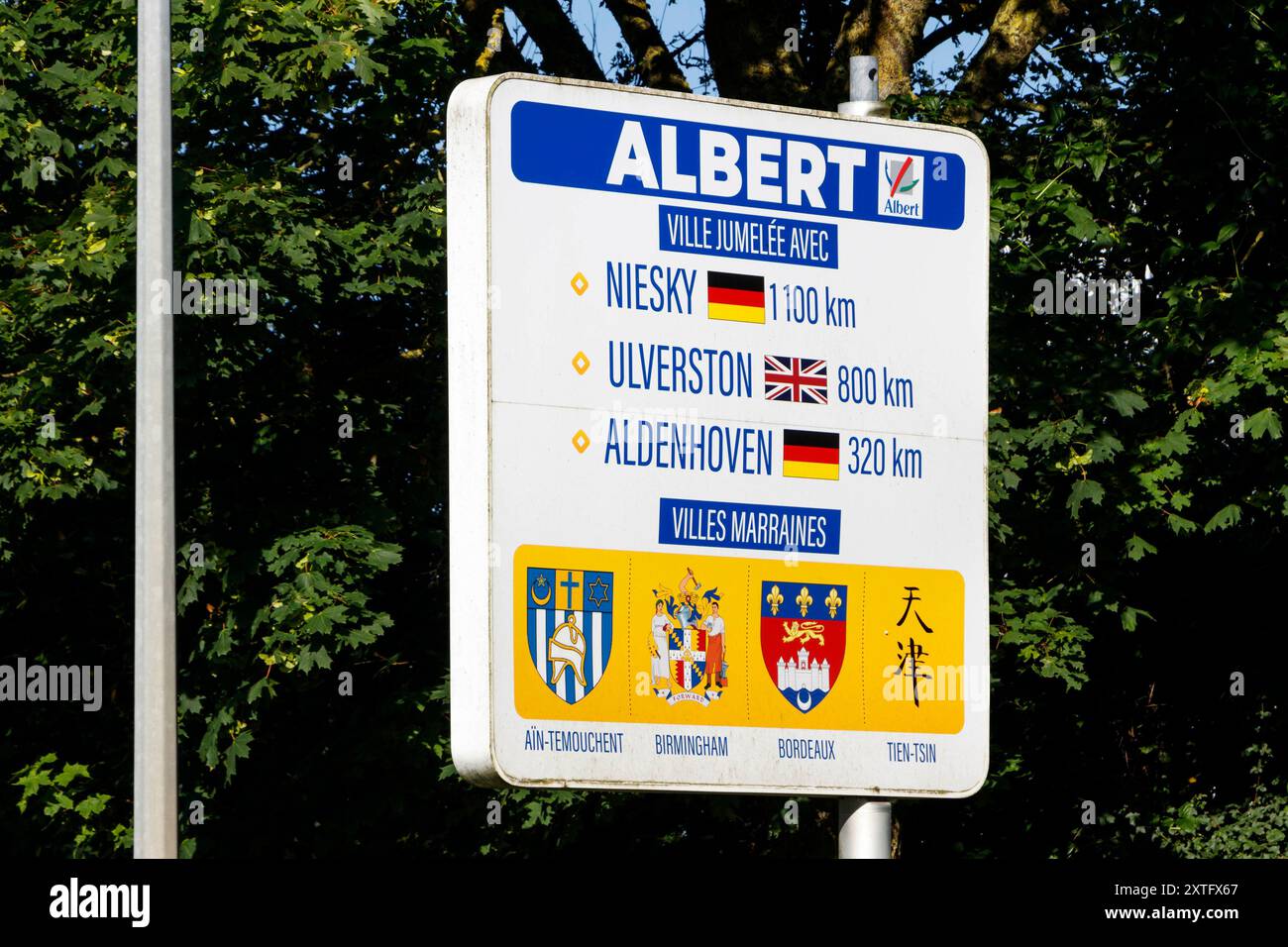 Richtungsschild in Albert, Frankreich, zeigt die Entfernung der Schwesterstadt zu Niesky, Ulverston und Aldenhoven an, mit entsprechenden Flaggen und Logos. Stockfoto