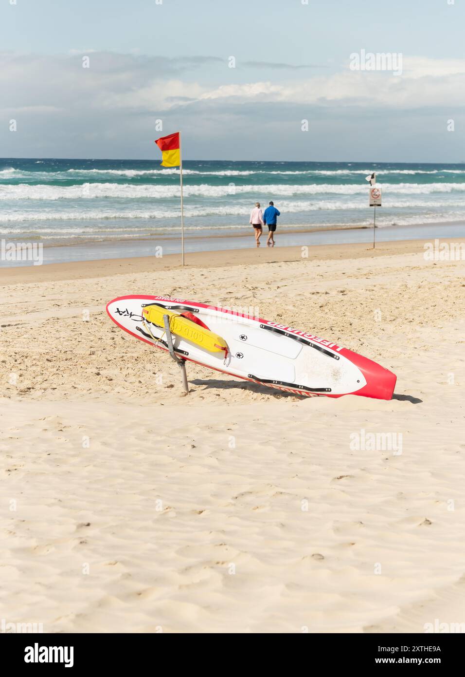 Ältere Ehepaare gehen am Ufer des Surfers Paradise, Queensland, Australien. 11. August 2024, mit Rettungsschwimmer-Ausrüstung mit Surfbrett. Stockfoto