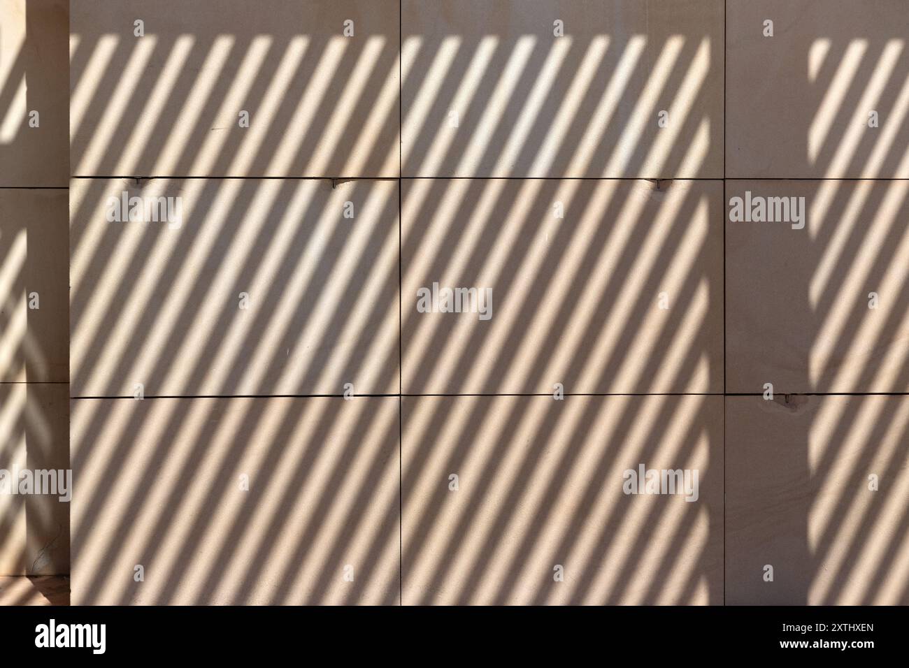 Diagonale Schatten auf cremefarbenen Steinwänden zur Verwendung als Hintergrundstruktur Stockfoto