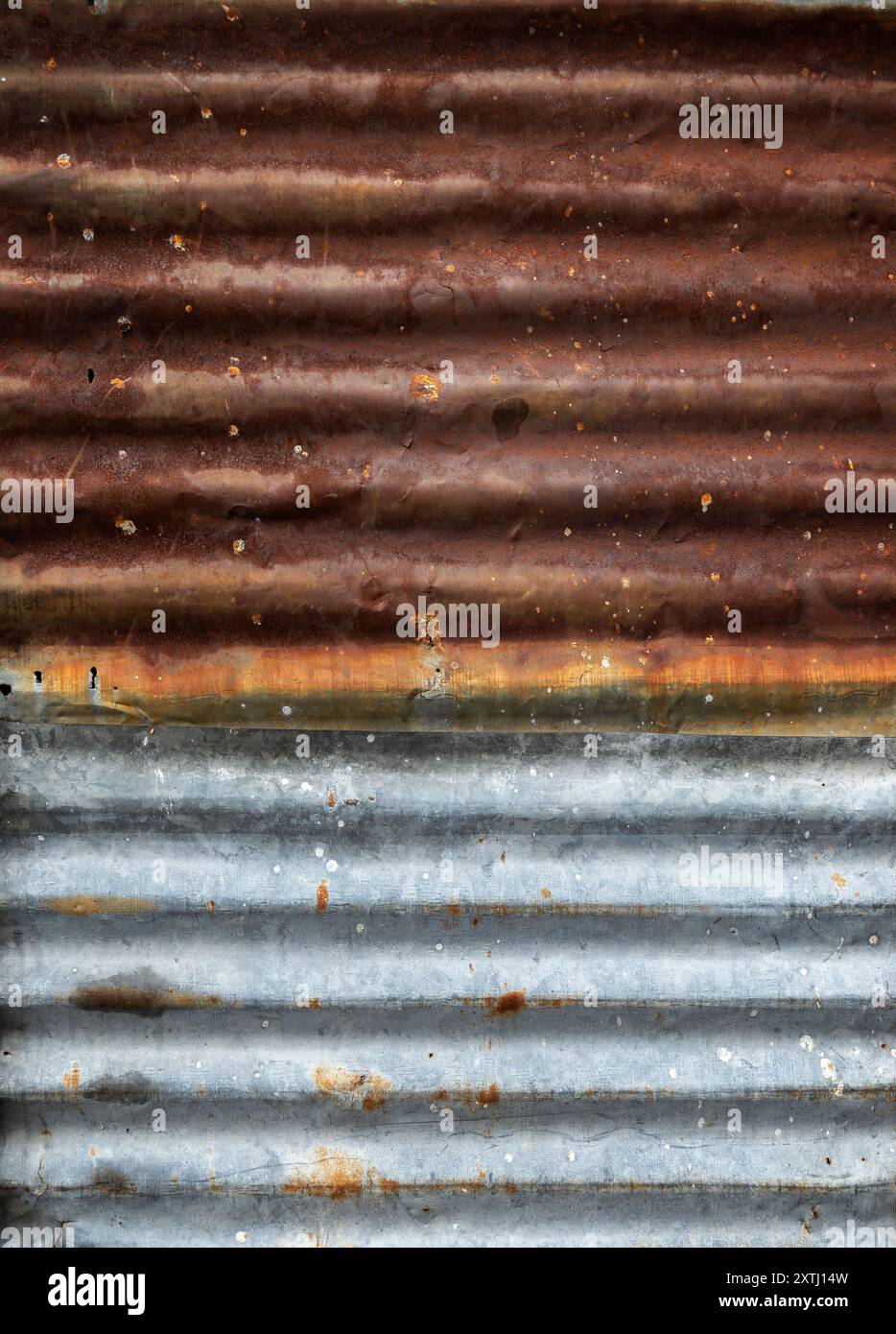 Nahaufnahme einer rostigen und verwitterten Baustellenwand aus Wellblech, von vorne gesehen. Abstrakter strukturierter Rosthintergrund. Stockfoto