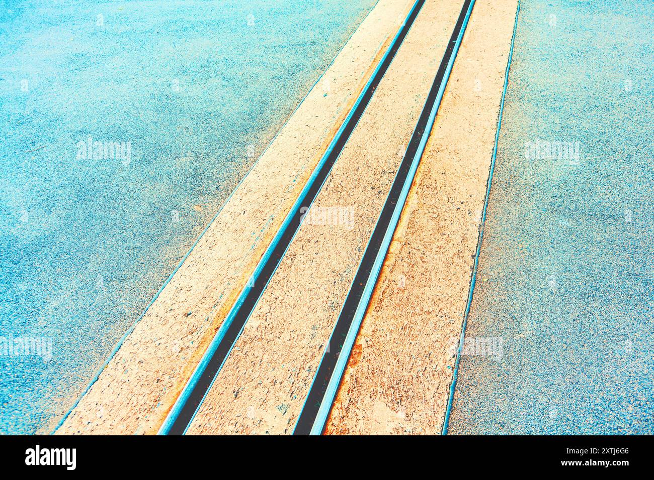 Eisenbahngleis mit zwei parallelen Gleisen. Die Gleise bestehen aus Beton und befinden sich auf einer asphaltierten Straße. Straßenbahnfahrt im Hintergrund, Showca Stockfoto