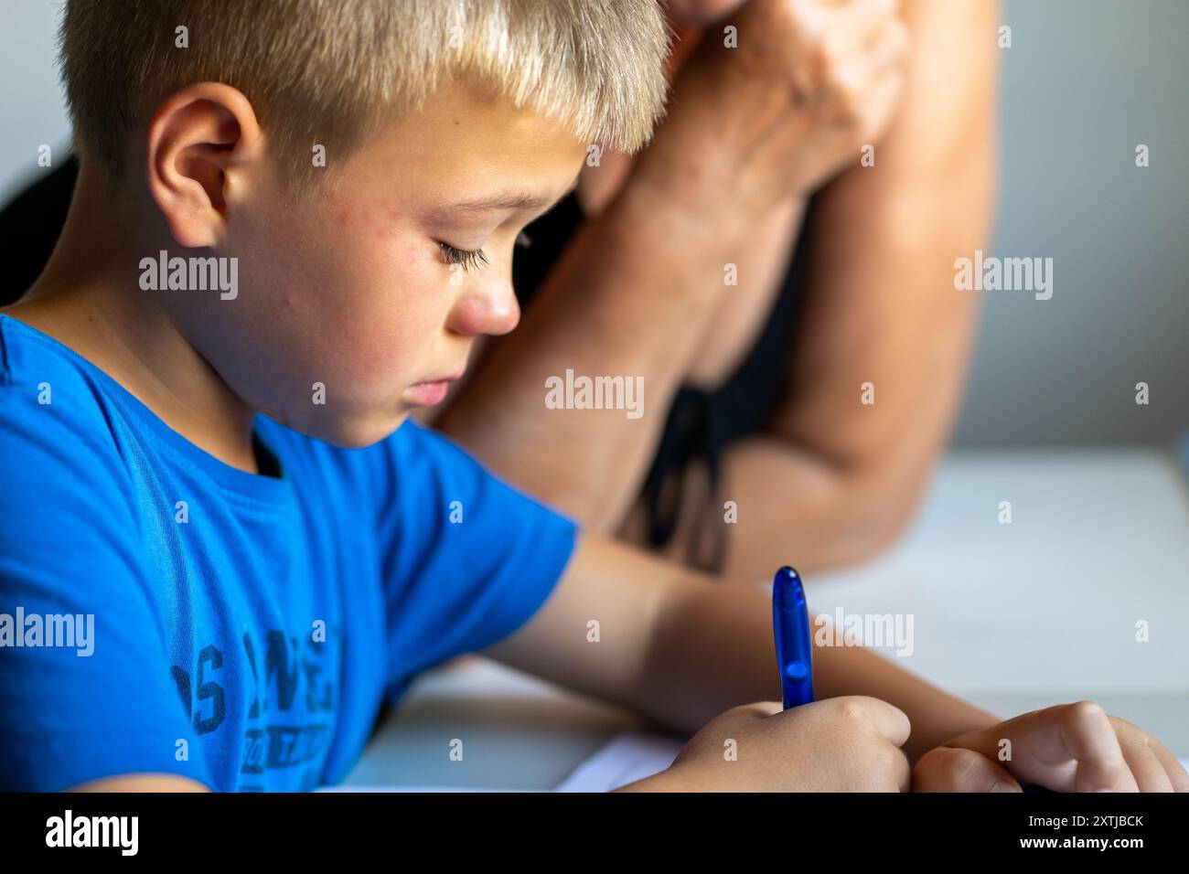 Ein Junge in einem blauen T-Shirt weint über die Schule Stockfoto