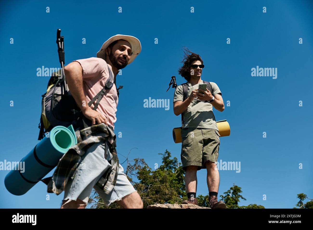 Zwei junge Männer, ein schwules Paar, wandern an einem sonnigen Sommertag zusammen in die Natur. Sie genießen die Natur und die Aussicht von einem hohen Punkt. Stockfoto