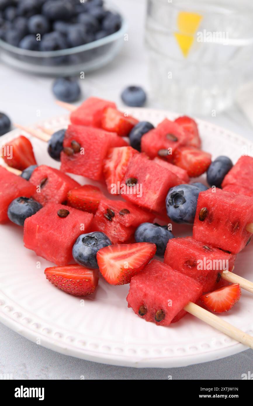 Spieße mit leckeren Wassermelonen, Erdbeeren und Heidelbeeren auf dem Tisch, Nahaufnahme Stockfoto