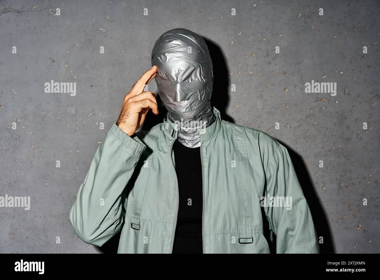 Geheimnisvoller, nachdenklicher Mann mit Klebeband-Gesicht auf grauem Hintergrund Stockfoto