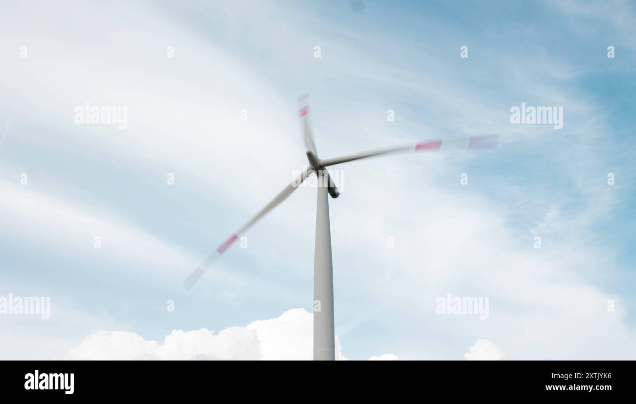 Windkraftanlage, grün Windenergieanlage mit rotierenden Rotorblättern, Wolken im Hintergrund. Die Enden der Klingen sind verschwommen. Windturbine B97A7758 Stockfoto