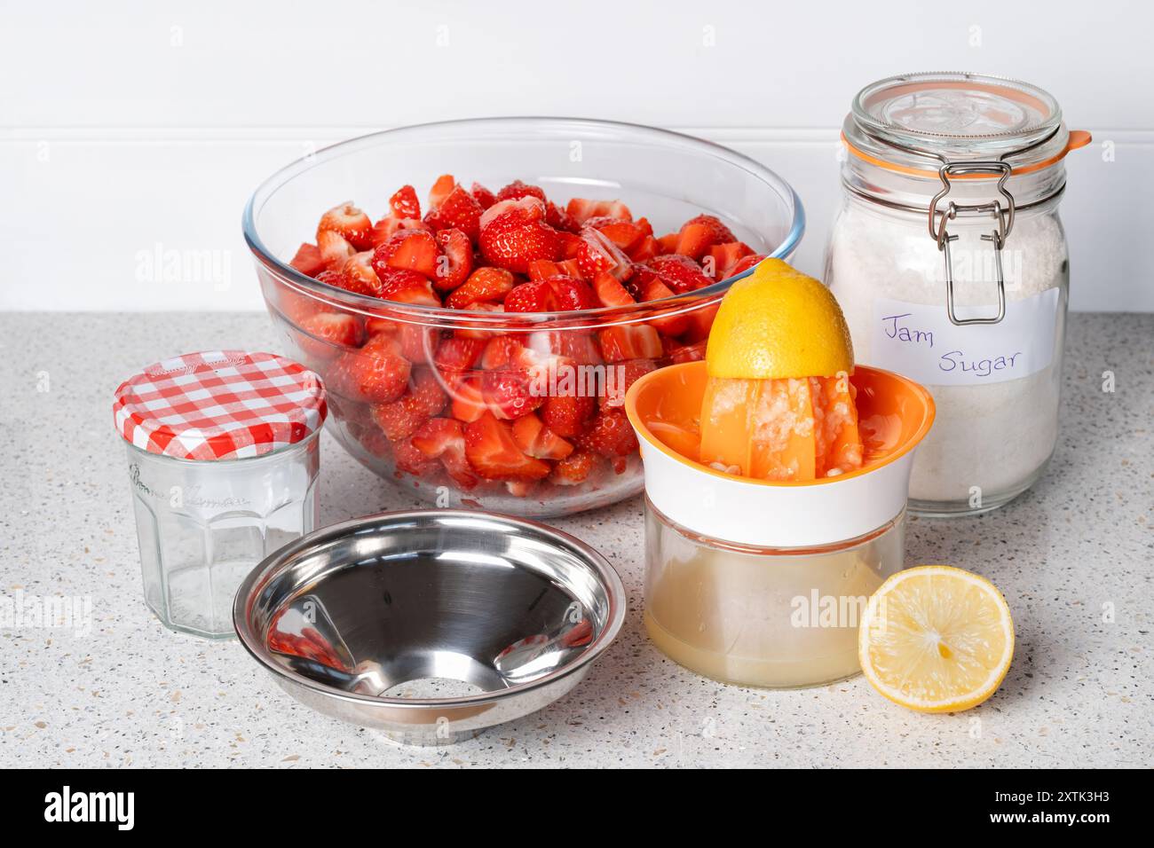 Die Zutaten für die Herstellung von hausgemachter Erdbeermarmelade werden vor der Herstellung von Marmeladen auf einem Tisch abgelegt Stockfoto