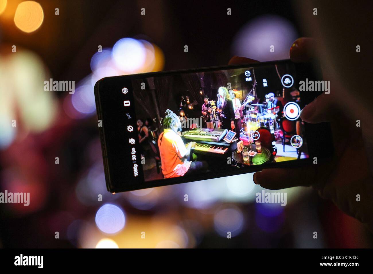 (240815) -- HAIKOU, 15. August 2024 (Xinhua) -- ein Publikum filmt Videos von David Mouk in einer Musikbar in Haikou, südchinesischer Provinz Hainan, 6. August 2024. Als Klavierlehrer und Bandmann kommt David aus der Republik Kongo und lebt seit fast 10 Jahren in Hainan. Nachdem er seit seiner Kindheit Musik studiert hatte, gründete er seine eigene Band während seines Studiums und kam später für einen Master-Abschluss hierher. Der Musiker ist fest davon überzeugt, dass Musik ein unverzichtbarer Bestandteil des Lebens ist und den Menschen Kraft verleihen kann. Deshalb gründete er ein Musikstudio, um Kindern das Klavierspielen beizubringen. Outi Stockfoto