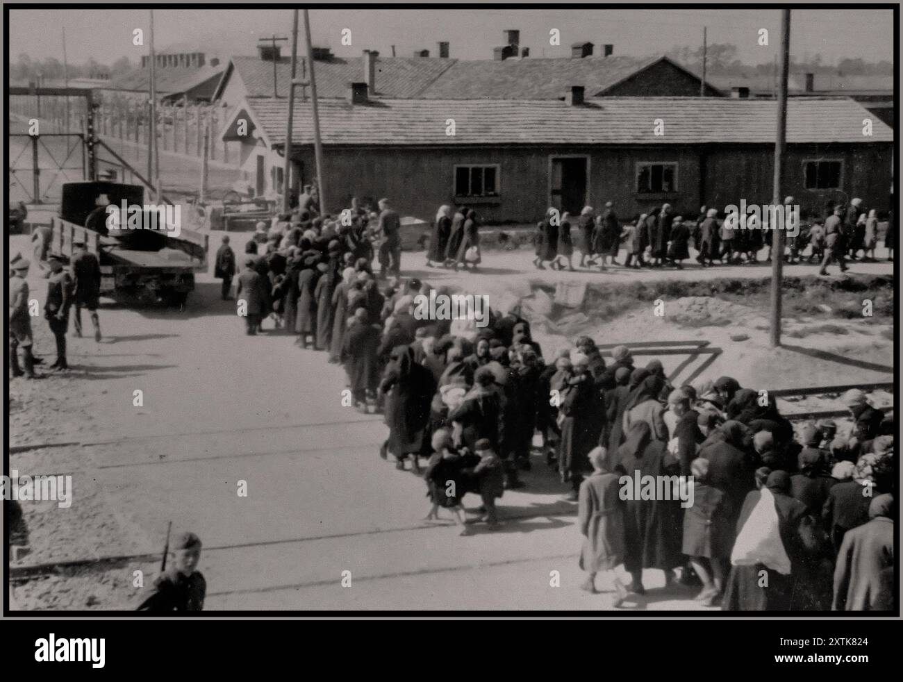 WW2 AUSCHWITZ Jüdische Frauen und Kinder, die zum Tod ausgewählt wurden, gehen unwissentlich in einer Schlange zu den Gaskammern. Ein schroffes und erschütterndes Bild des bevorstehenden Todes im industriellen Maßstab. Das Tor oben links führt zum Abschnitt des Lagers auf der Südseite der als BI bekannten Rampe. Fotograf Bernhardt Walter/Ernst Hofmann Datum Mai 1944 Auschwitz, [Oberschlesien] Polen Stockfoto