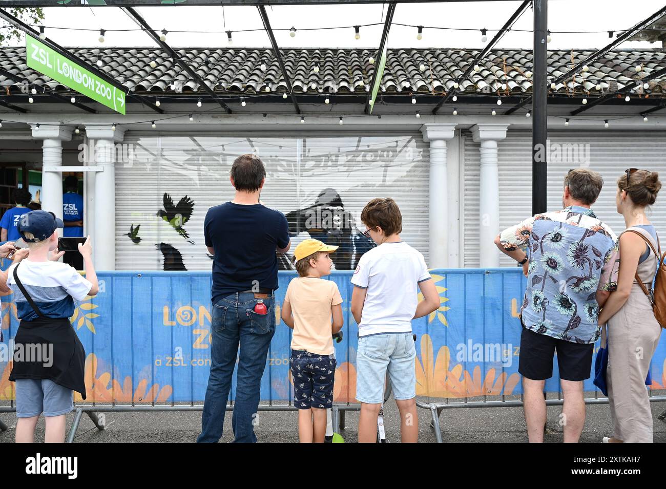 Das letzte Stück von Banksys Animals-Serie wurde am frühen Dienstag, dem 13. August morgens im Londoner Zoo enthüllt und zeigt einen Gorilla, der ein Tor hebt, während verschiedene Tiere, darunter ein Seelöwe und ein Trio neugieriger Augen, im Hintergrund zu sehen sind . Sie hat viele Besucher und Medien auf sich aufmerksam gemacht . Die Passanten waren von einer Überraschung begeistert. Stockfoto