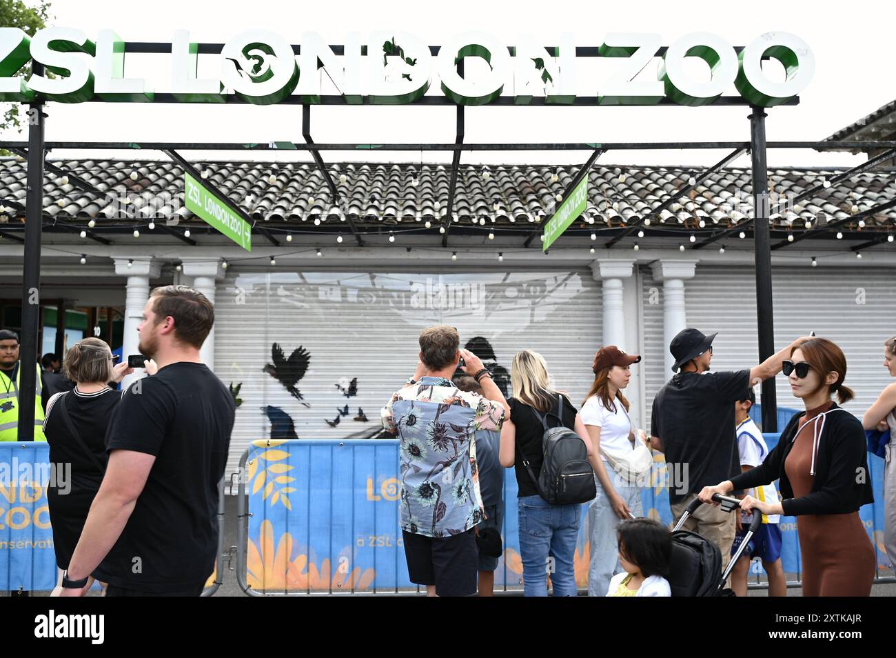 Das letzte Stück von Banksys Animals-Serie wurde am frühen Dienstag, dem 13. August morgens im Londoner Zoo enthüllt und zeigt einen Gorilla, der ein Tor hebt, während verschiedene Tiere, darunter ein Seelöwe und ein Trio neugieriger Augen, im Hintergrund zu sehen sind . Sie hat viele Besucher und Medien auf sich aufmerksam gemacht . Die Passanten waren von einer Überraschung begeistert. Stockfoto