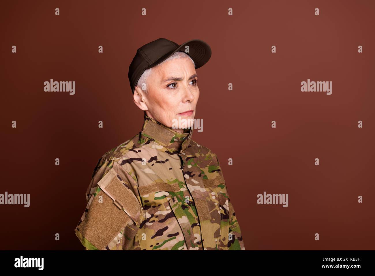 Foto einer selbstbewussten starken pensionierten Frau tragen Tarnfarbe, die leeren Raum aussieht, isolierter brauner Hintergrund Stockfoto