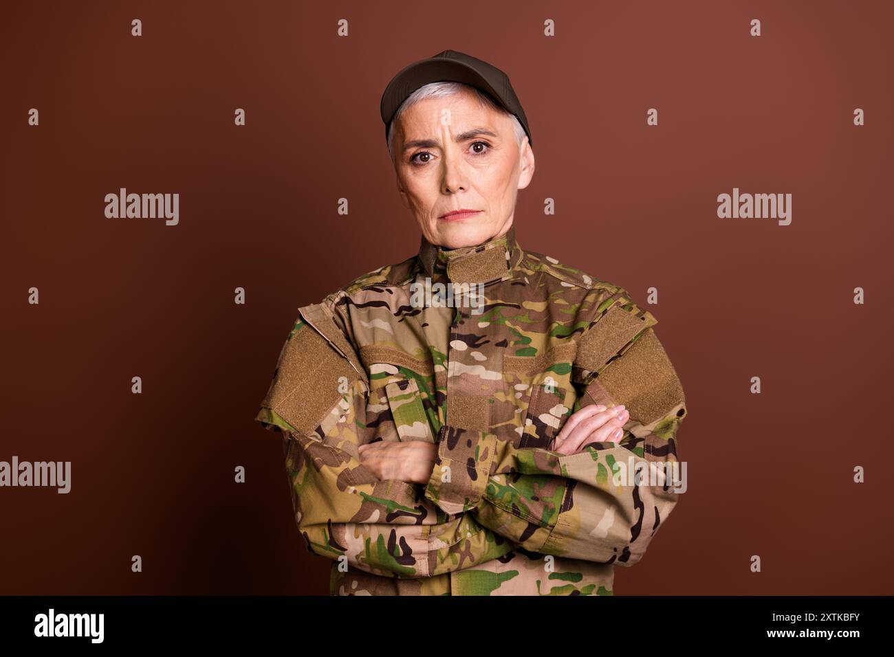 Foto von Militär-selbstbewussten Seniorinnen tragen Tarnarme durchkreuzten leeren Raum isolierten braunen Hintergrund Stockfoto