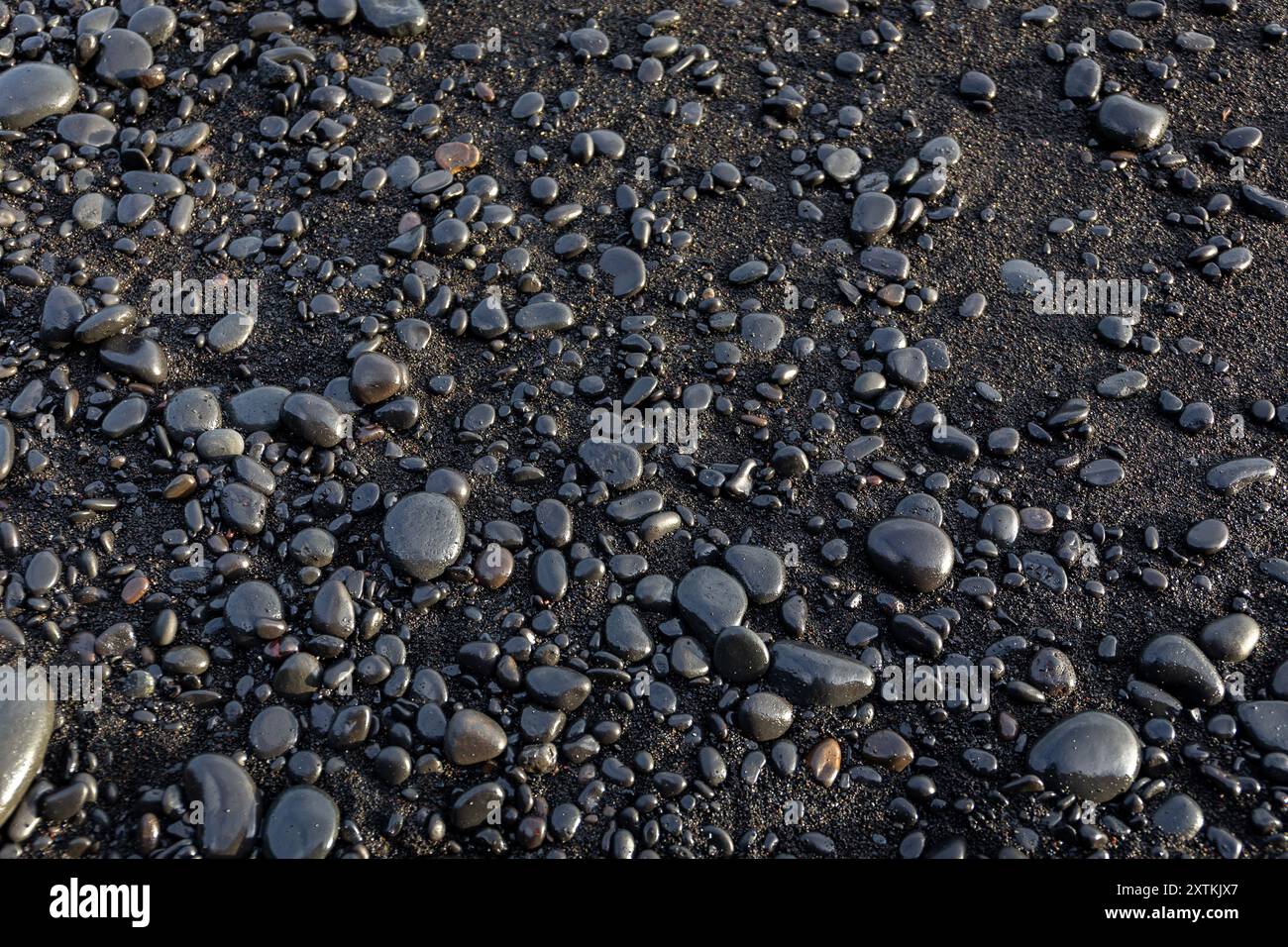 Glänzende Basaltsteine Hintergrund auf schwarzem Sand, Reynisfjara Black Sand Beach, Island, Blick von oben. Stockfoto