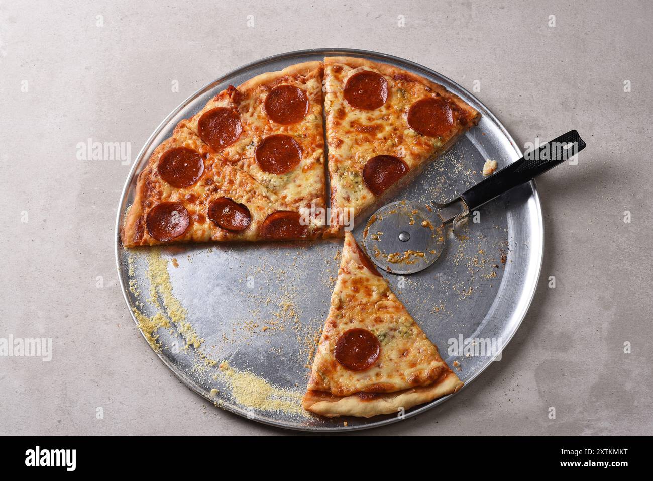 Blick von oben auf eine hausgemachte Pizza auf einer Pfanne mit fehlenden Scheiben und einem Pizzaschneider. Stockfoto