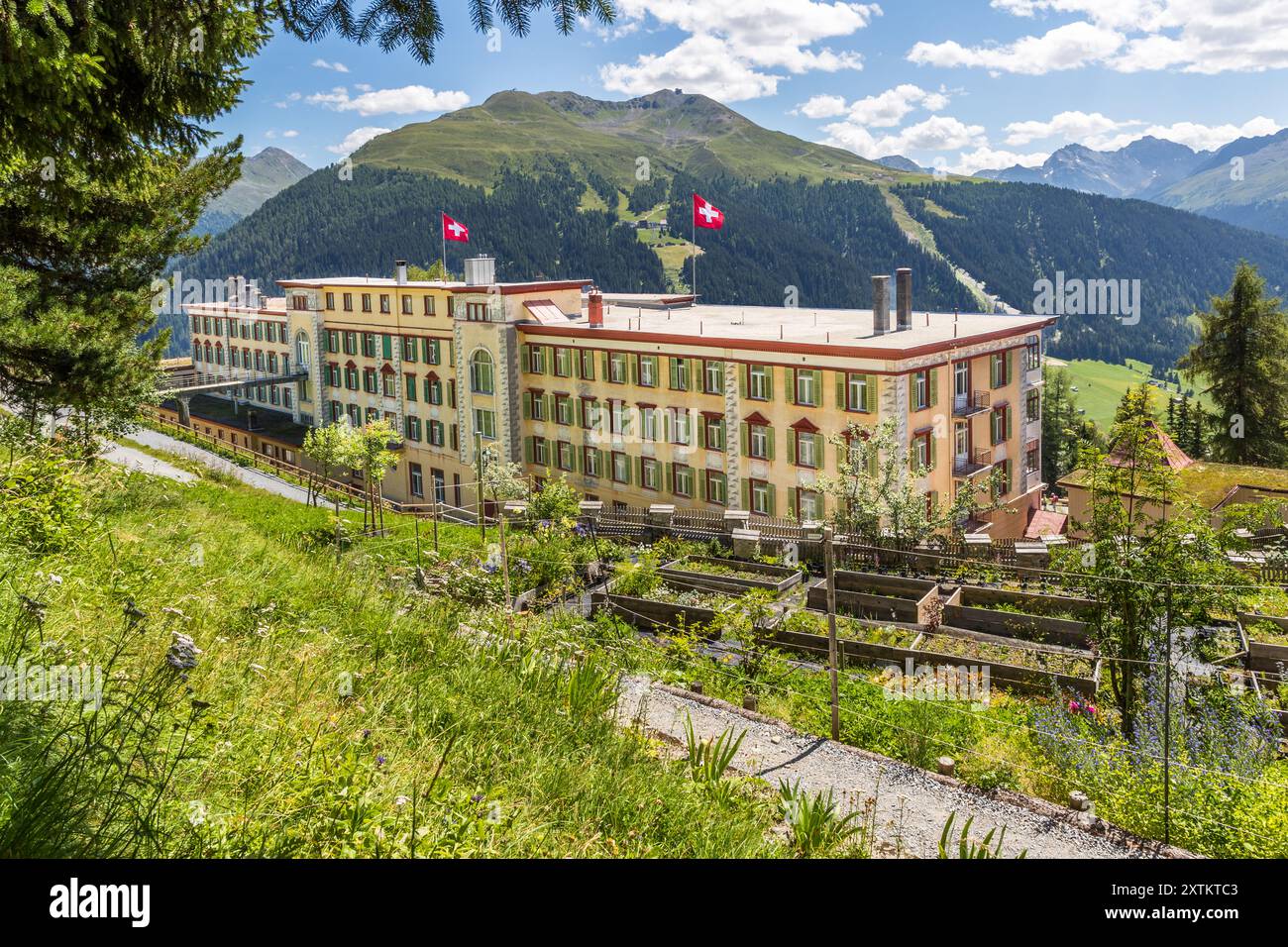 Rückansicht mit Brücke auf der Seite des ehemaligen Sanatoriums Schatzalp gegenüber dem Berg diente als Hintereingang und wurde für logistische Zwecke genutzt. Sie verschaffte dem Personal Zugang zum Gebäude und diente zur Lieferung von Waren und Vorräten. Das ehemalige Sanatorium Schatzalp oberhalb von Davos. Heute ist es ein Hotel. Thomas-Mann-Weg, Davos, Graubünden, Schweiz Stockfoto