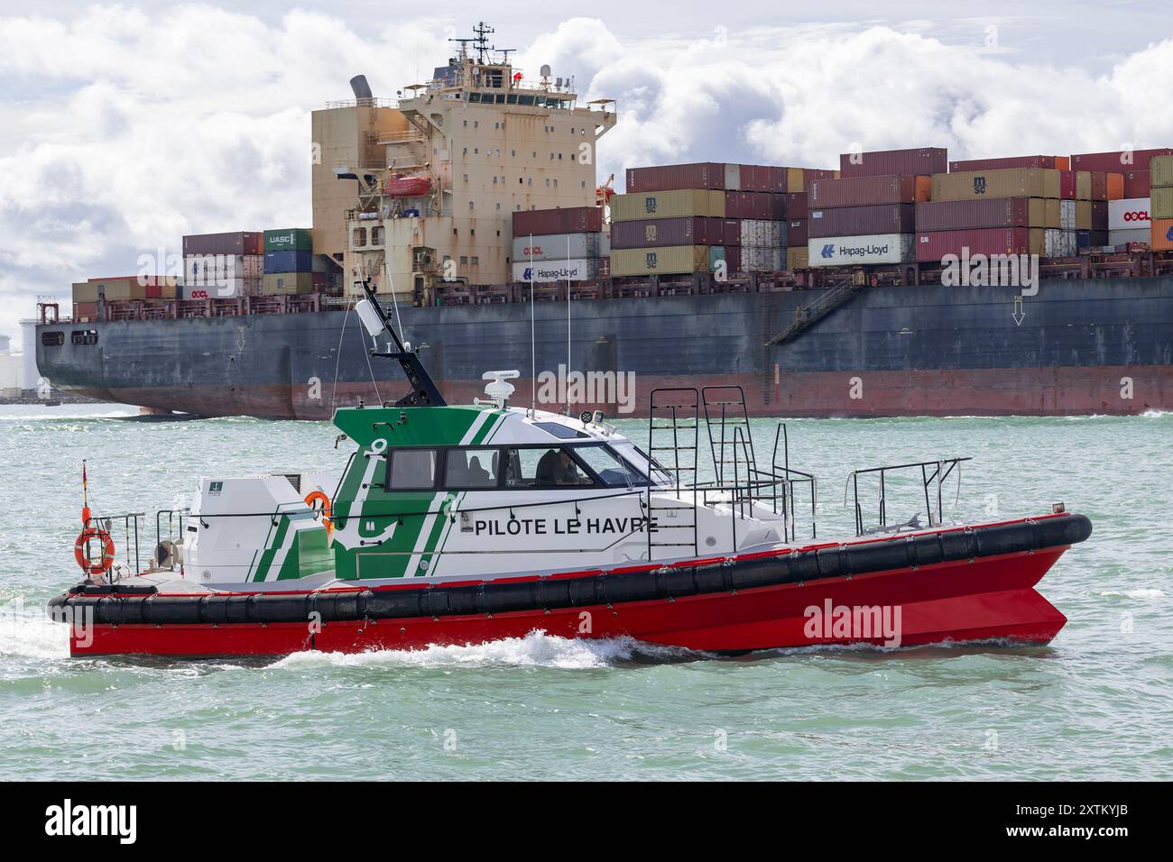 Le Havre, Frankreich - Blick auf das Lotsenboot SAINTE HONORINE, ausgehend vom Hafen von Le Havre mit einem Containerschiff dahinter. Stockfoto