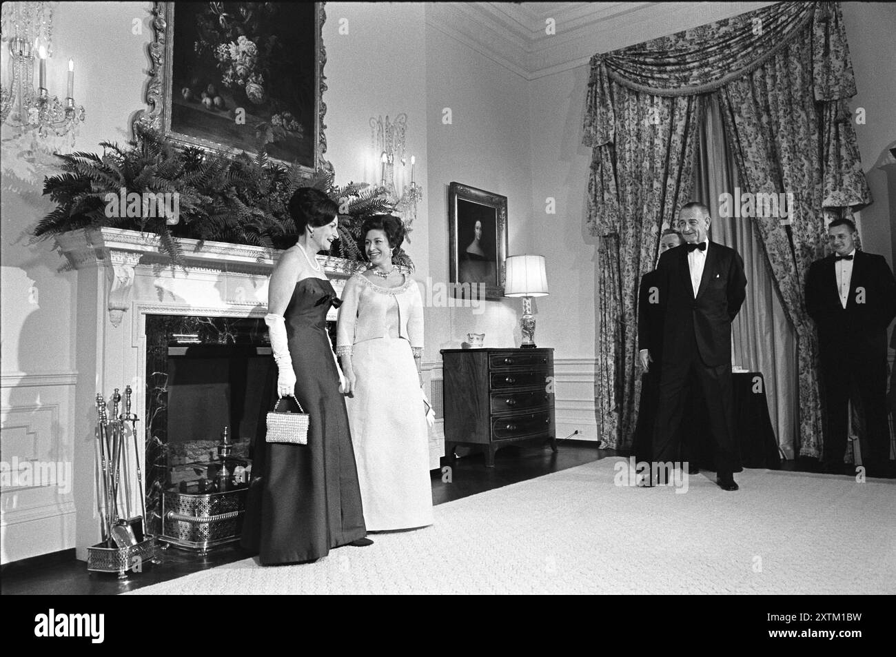 Lady Bird Johnson und Prinzessin Margaret von Großbritannien posieren vor dem Kamin, US-Präsident Lyndon Johnson und Antony Armstrong Jones (teilweise hinter Johnson verdeckt) schauen zu, Queen's Room, Weißes Haus, Washington, D.C. USA, Yoichi Okamoto, 17. November 1965 Stockfoto