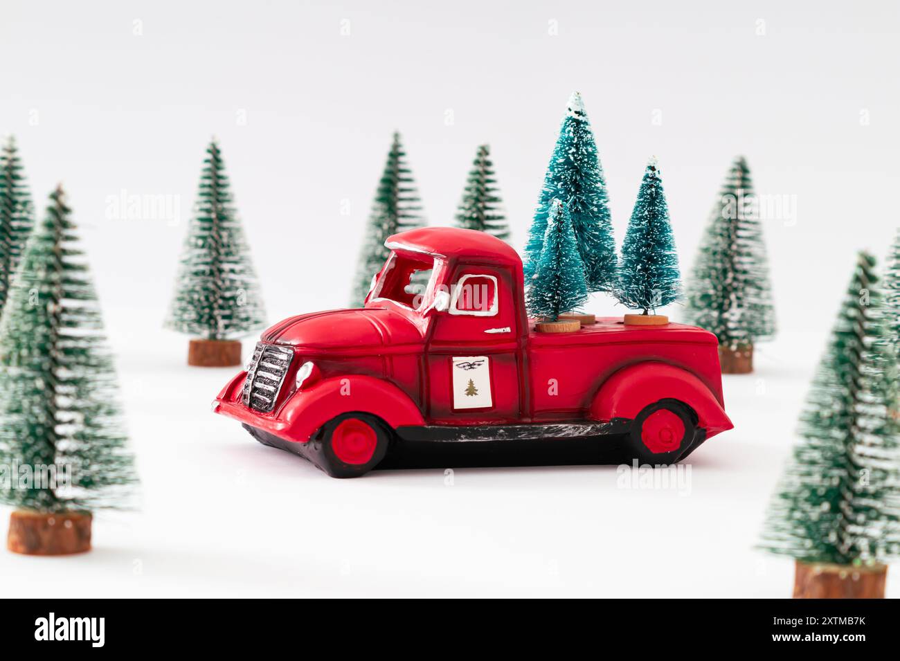 Kreatives Layout mit rotem Weihnachts-Retro-Truck und grünen Weihnachtsbäumen auf weißem Hintergrund. Minimales Weihnachts- und Neujahrskonzept. Stockfoto