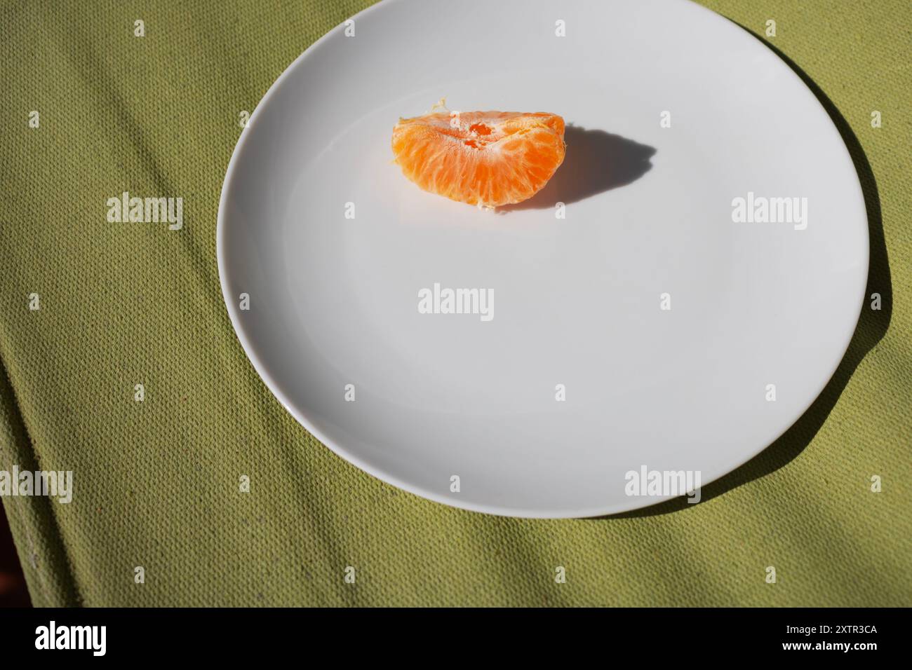 Clementine Keile auf einer weißen Platte mit grünem Hintergrund, bei Sonnenlicht Stockfoto