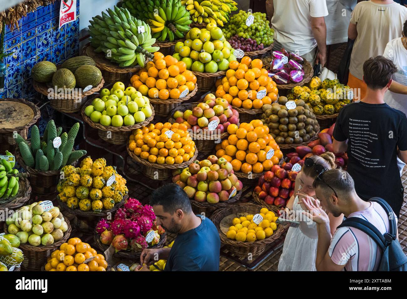 Touristen probieren einige der farbenfrohen frischen Früchte auf dem Markt Mercado dos Lavradores im Herzen von Funchal, Madeira, der am 6. August 2024 gesehen wurde. Stockfoto