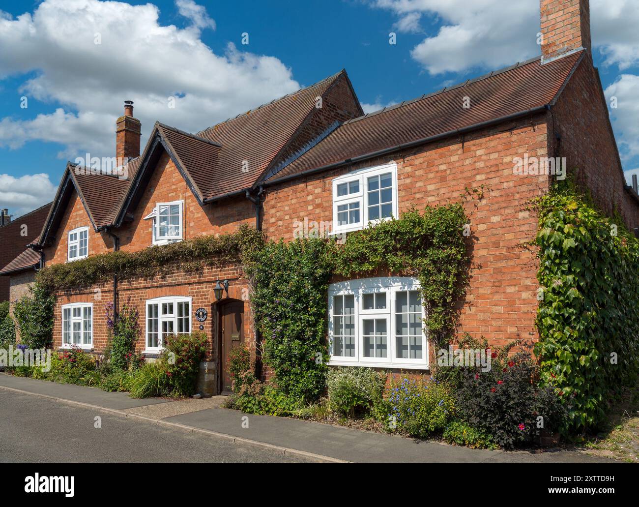 Alt, hübsch, englisch, roter Backstein, 'Bakery Cottage' im Sommer mit blauem Himmel und Kletterpflanzen, Burton Lazars, Leicestershire, England, Großbritannien Stockfoto