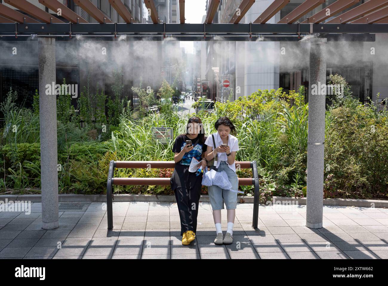 Touristen ruhen sich an einem sonnigen Tag in Ginza unter einer Kühlstation aus. „Obwohl die Temperaturen in Tokio aufgrund der globalen Erwärmung jeden Sommer neue Hitzeskorde erreichen, steigt die Zahl der Touristen. Die Zahl der Touristen, die Japan besuchen, ist derzeit höher als zu Zeiten vor covid.“ (Foto: Stanislav Kogiku / SOPA Images/SIPA USA) Stockfoto