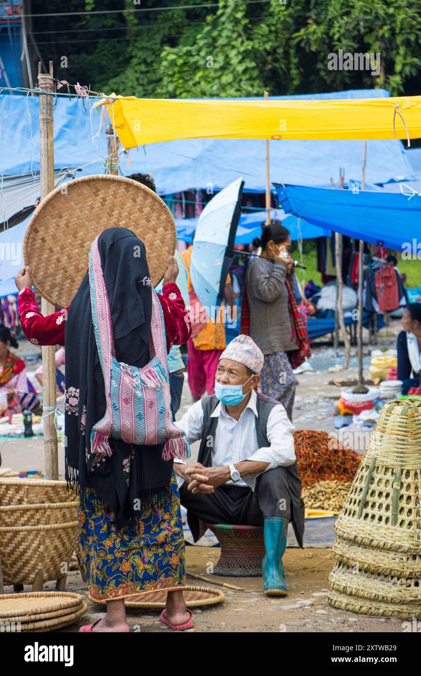 Eine Frau überprüft Nanglo, ein Korbtablett auf einem Haat Basar in Khandbari, Sankhuwasabha Bezirk. Nepal. Nanglo ist ein praktisches Küchengerät in Nepal. Stockfoto