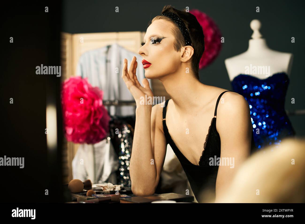 Ein Drag-Performer schminkt sich vor einer Vorstellung und sitzt an einem Frisiertisch. Stockfoto