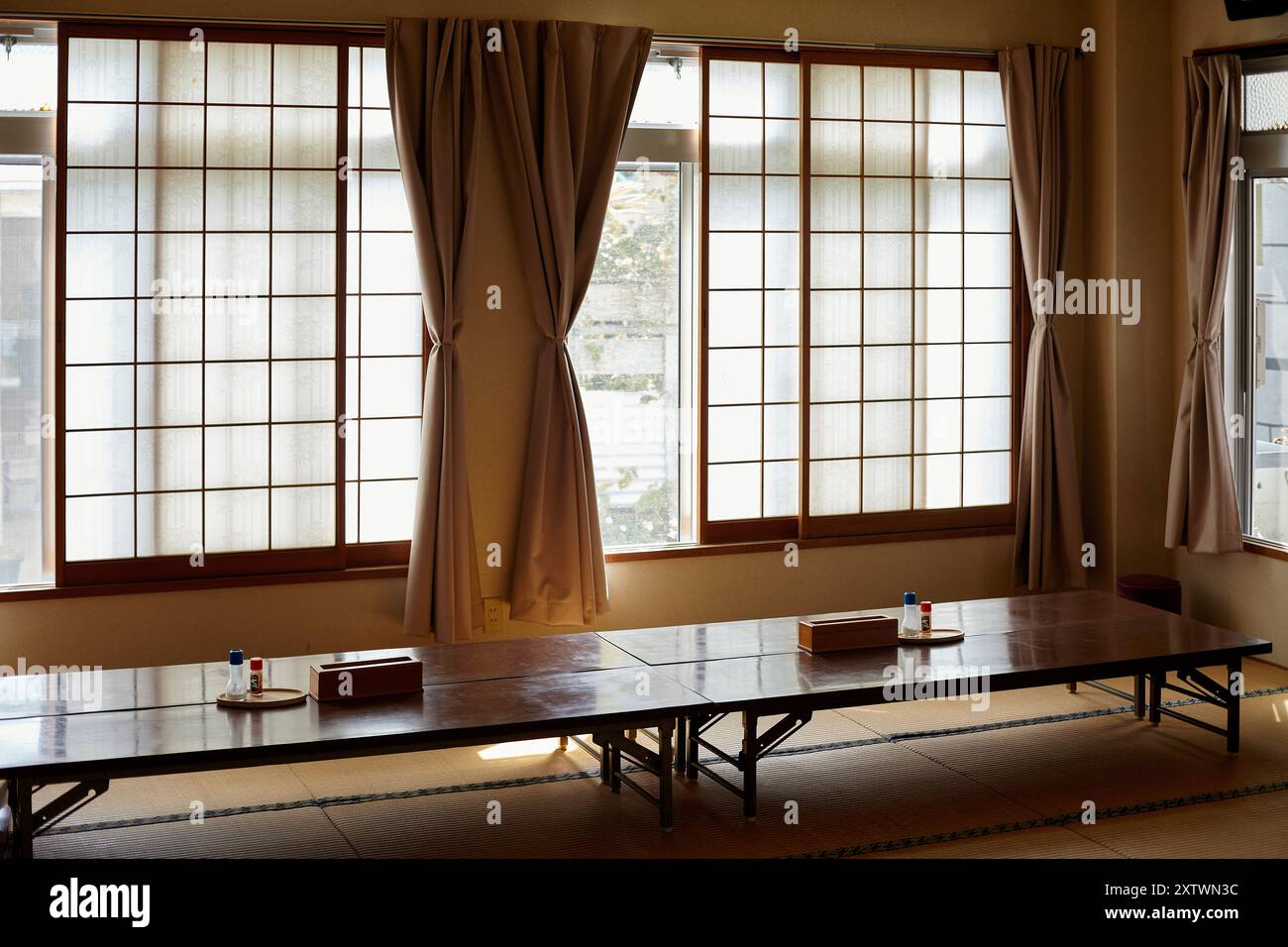 Traditioneller japanischer Speisesaal mit niedrigem Holztisch, Tatamimatten und Schiebetüren aus Shoji-Papier. Stockfoto