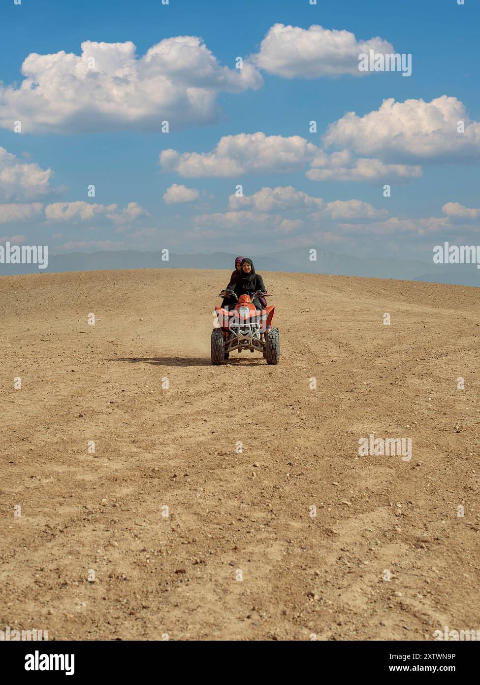 Eine Person, die ein Quad auf einem staubigen Weg mit klarem blauem Himmel über dem Kopf fährt. Stockfoto